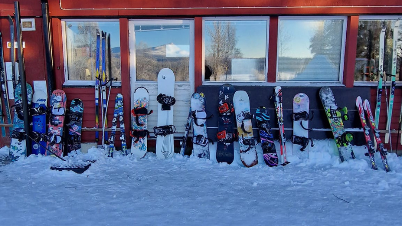 Väggen utanför Saxnäs fjällskola är full av brädor och skidor. Foto: Åza Nejne.